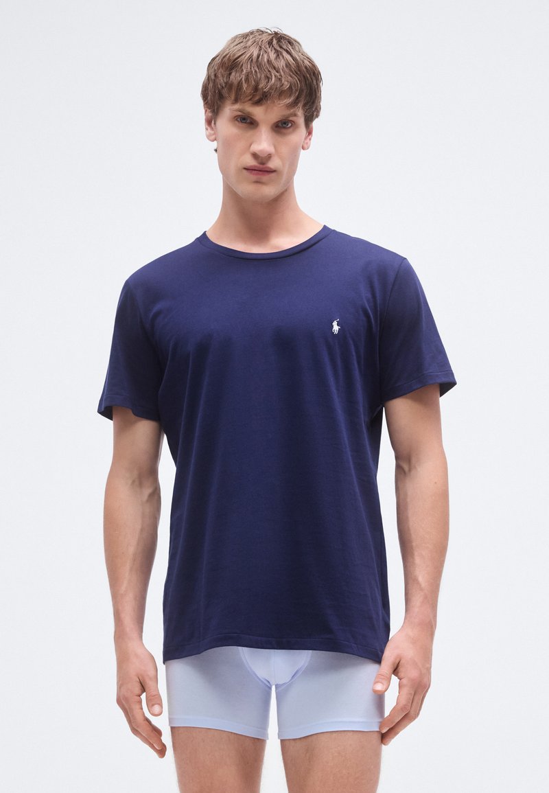 T-shirt de algodão azul-marinho com gola redonda e mangas curtas, com um pequeno logótipo branco na área do peito esquerdo.