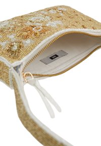 Beadasta torbica z zlatim, teksturiranim zunanjim slojem, ki vsebuje cvetlične vzorce in bele akcentne. Notranjost je podložena z bež tkanino in ima oznako.