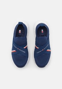 Marinblå stickade sneakers med ett korsat band och röda, vita och blå accenter. Vit gummisula. "Tommy Hilfiger"-logotypen ingår.