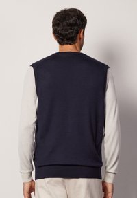 Mörkblå ärmlös tröja tillverkad av mjukt tyg, med ribbad nederkant och kontrasterande ljusgrå långärmar. Minimalistisk design, utan mönster.