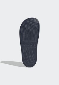 Jasnoszary kolor klapek Adidas, z teksturowaną podeszwą w wzór jodełki, z wytłoczonym logo marki. Owalne segmenty na pięcie dla lepszej przyczepności.