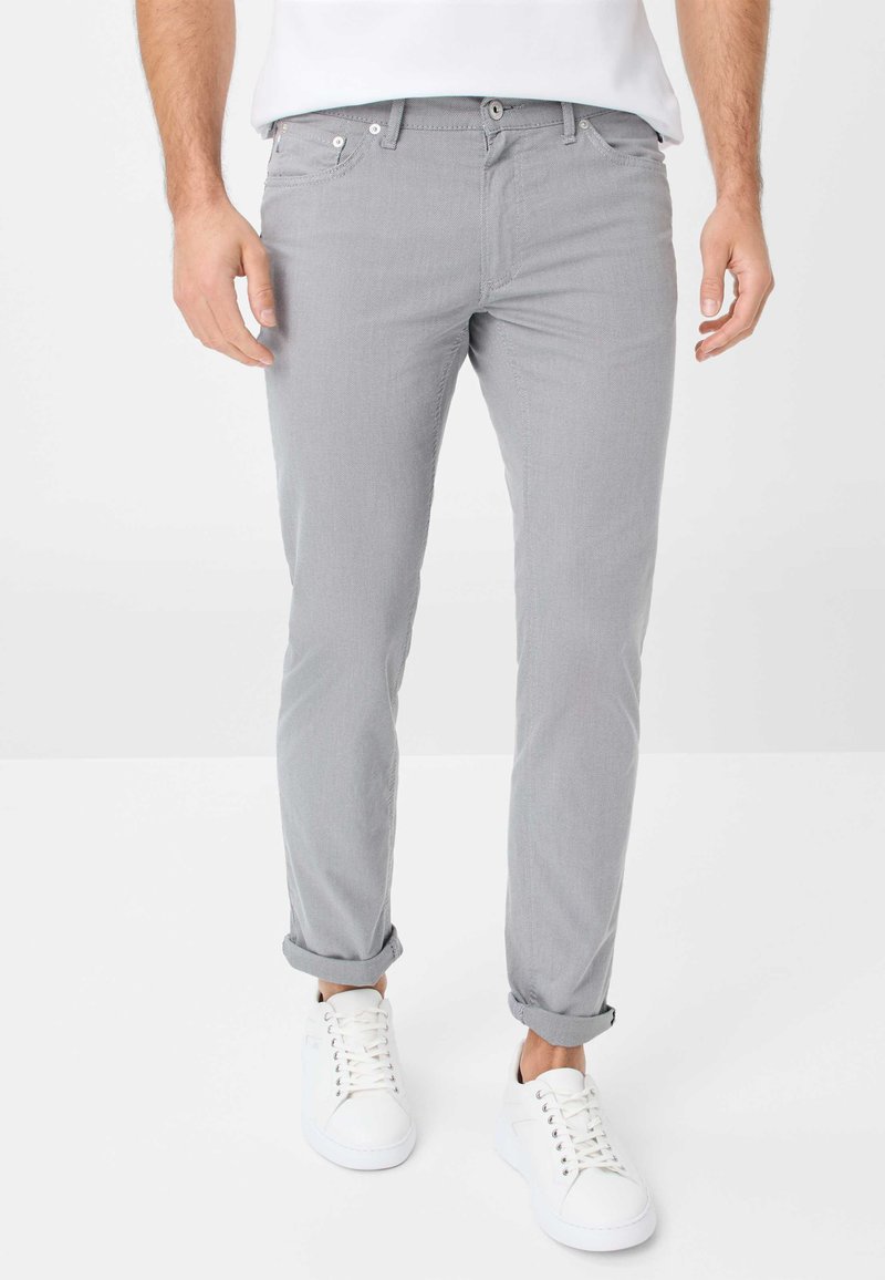 Hellgraue Hosen mit schlankem Schnitt, die eine glatte Textur und hochgekrempelte Säume aufweisen, kombiniert mit weißen Turnschuhen. Klassisches Design mit Fronttaschen.