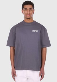 Tricou din bumbac gri, cu mâneci scurte, guler rotund și text alb "DROPSIZE" imprimat pe pieptul stâng. Croială simplă, relaxată.