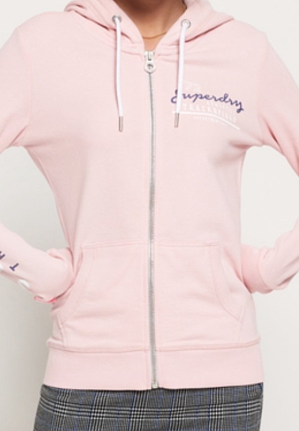 Sudadera con cremallera en rosa claro, con cremallera frontal, cordones y bolsillos laterales. Marca notable en el pecho y la manga.