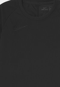 Camiseta deportiva Dri-FIT negra con cuello redondo y mangas raglán. Sutil logo negro de Nike en la parte superior izquierda del pecho. Tejido suave y liso.