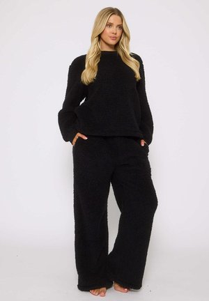 Ensemble de loungewear molletonné noir et fluffy comprenant un haut à manches longues et un pantalon large et ample, conçu pour le confort avec des poches latérales.