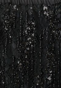 Sort blonde stof har intrikate mønstre prydet med palietter og perler. Teksturen er gennemsigtig med en lagdelt, reflekterende kvalitet.