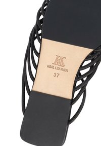 Μαύρη δερμάτινη σαγιονάρα με λουράκια, με μπεζ εσωτερική σόλα που φέρει τη σφραγίδα «KS Real Leather 37», που υποδεικνύει την επωνυμία, το υλικό και το μέγεθος.