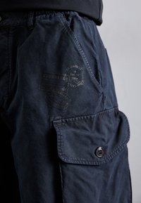 Pantalones cargo de la marina hechos de tela suave, con una cinturilla elástica, bolsillos laterales y un bolsillo frontal con detalles de estampado de marca.