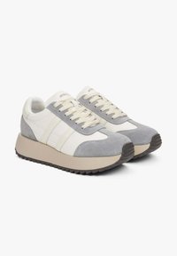Witte en grijze sneakers gemaakt van suede en leer, met een ronde neus, beige plateauzool en crèmekleurige veters. Twee zijstrips op elke schoen.