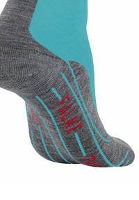 Calzino sportivo grigio con accenti turchesi e logo rosso. Materiale testurizzato con motivo a grip sulla suola per una presa migliore.