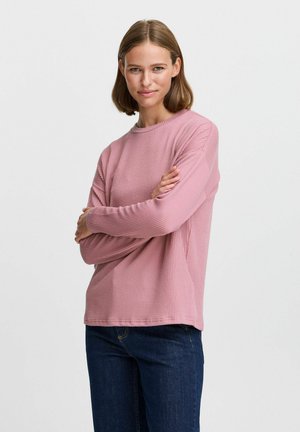 Long-sleeve, ribbed crew-neck sweater in light pink, made of textured fabric; paired with dark denim jeans.