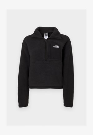 Zwarte fleece pullover met een kwart rits, hoge kraag en een borstzak met een wit logo. Zachte textuur en cropped ontwerp.