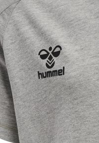 Grå bomullströja med en svart logotyp och texten "hummel", med en mjuk textur och korta ärmar. Enkel, avslappnad design.
