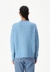 Hellblaues Strickpullover mit strukturiertem Muster, Rundhalsausschnitt und langen Ärmeln. Gerippte Bündchen und Saum; leicht lockere Passform.