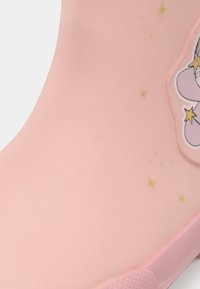 Stivale da pioggia per bambini rosa con disegni di unicorno viola e stelle gialle sul lato.