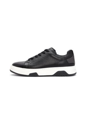 Black textured leather low-top sneaker with black laces and thick white sole with black tread on white background.