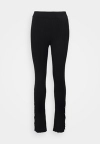 Svarta ribbade leggings med en åtsittande design, som har en bred midja och scalloperade fållar, prydda med dekorativa knappar på sidorna.