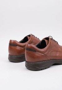 Brown leather shoes with rounded toe, stitched detailing, and cushioned soles. The design features a lace-up closure and textured accents.