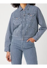 Blå och vit randig denimjacka med krage, två bröstfickor och framdragkedja, med ribbade muddar och nederkant för en figurnära look.