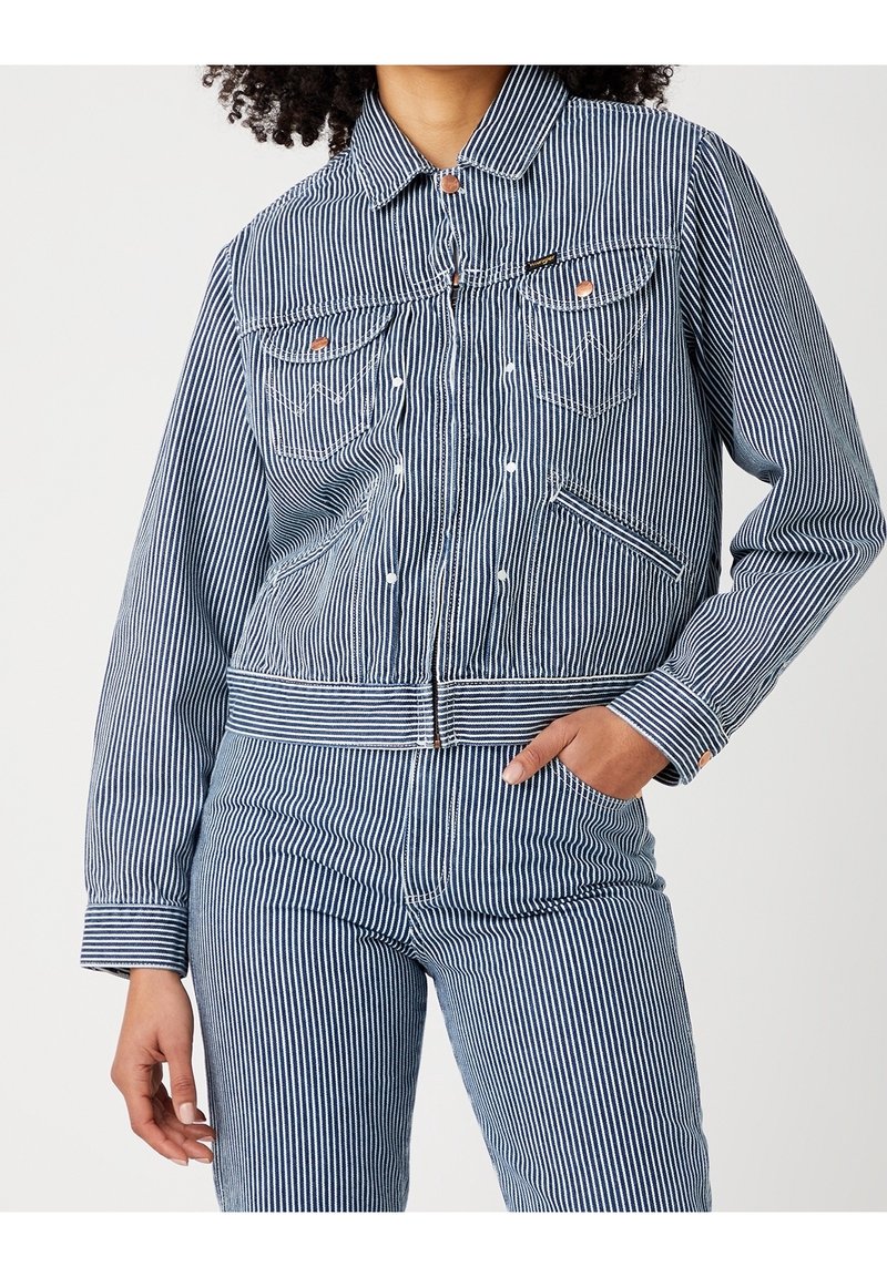 Blå och vit randig denimjacka med krage, två bröstfickor och framdragkedja, med ribbade muddar och nederkant för en figurnära look.