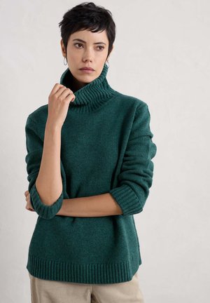 Pull en maille turquoise à col roulé avec un col et des poignets côtelés, affichant une coupe décontractée et un tissu texturé. Variations subtiles de couleur à travers le vêtement.