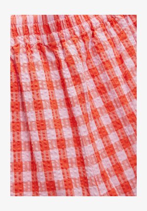 Tessuto a quadri rossi e rosa con una finitura texturizzata, caratterizzato da una vita arricciata e un design plissettato. Il materiale sembra leggero e traspirante.