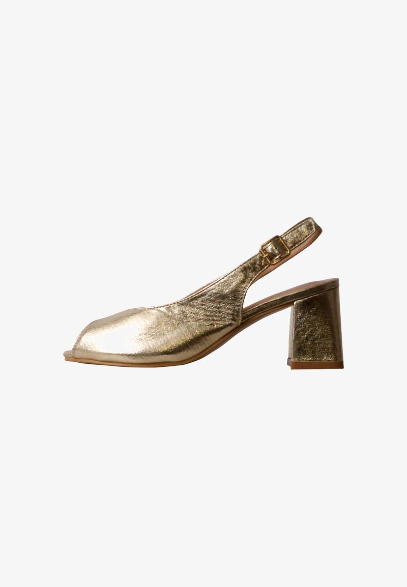Chaussure slingback en cuir métallique doré avec un petit talon bloc et une petite bride à boucle sur fond blanc.