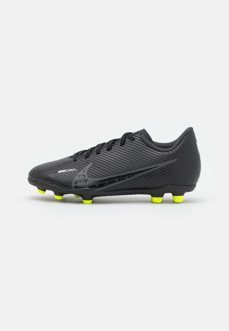 Botín de fútbol Nike Mercurial negro con tacos amarillos, diseño con cordones y patrón texturizado a rayas sobre un fondo blanco.
