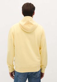 Geel katoenen hoodie met een trekkoord in de capuchon, ribbels bij de mouwen en de zoom. Heeft een gladde textuur en een ontspannen pasvorm. Geen zichtbare graphics.