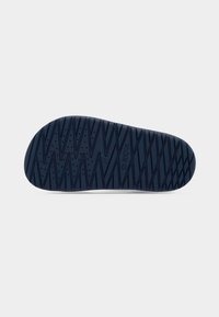 Granatowa gumowa podeszwa buta z teksturowanym wzorem zygzakowatym i otworami drenażowymi, z oznaczeniem marki Geox. Czysty i równy brzeg zapewniający przyczepność.