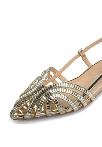 Zapato plano abierto en la parte delantera de tono dorado con correas entrecruzadas y acentos metálicos decorativos. Plantilla lisa en color beige con un diseño de punta afilada.
