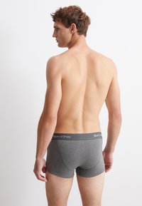 Graue Baumwollboxershorts mit engem Schnitt und elastischem Bund, auf dem der Markenname "Marc O'Polo" in hellgrauer Schrift zu sehen ist.