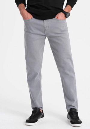 Lichtgrijze jeans met een rechte snit, met voorzakken en subtiele stikdetails. Gecombineerd met zwarte sneakers.