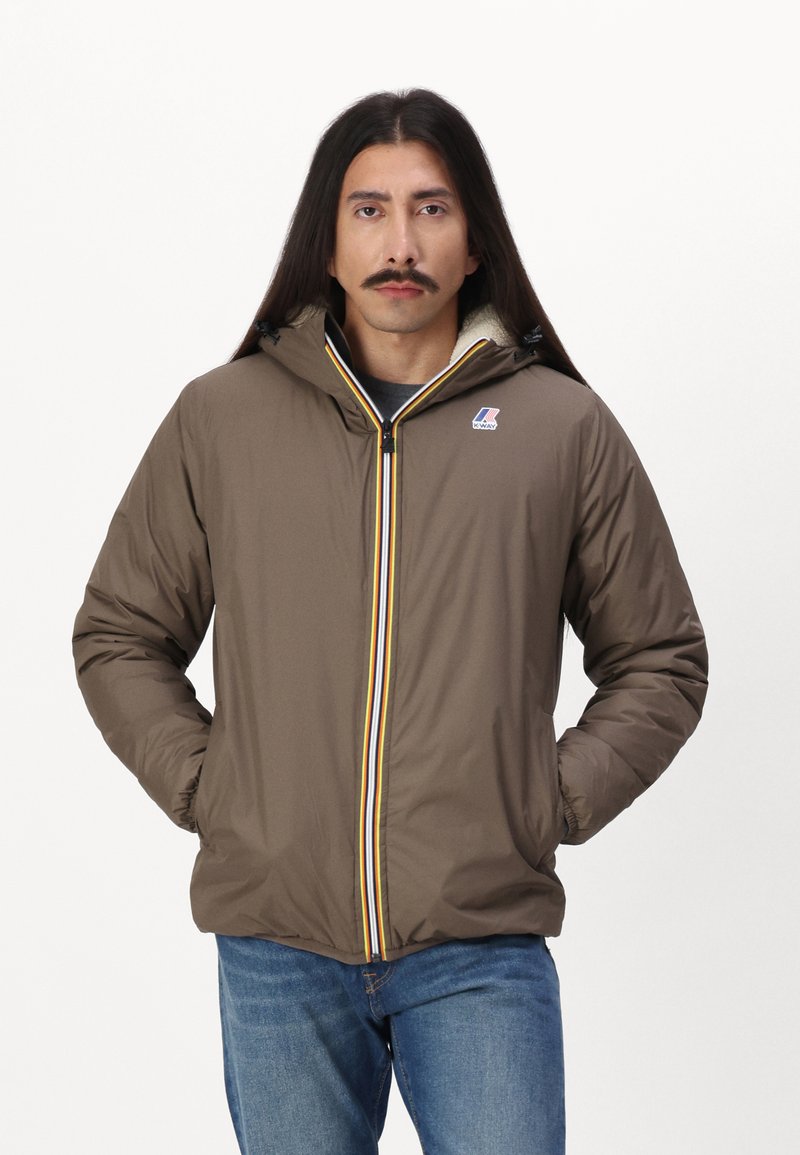 Giacca a vento marrone con zip frontale, strisce gialle e blu a contrasto e un morbido rivestimento interno. Presenta un cappuccio e tasche laterali.
