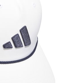 Casquette de baseball blanche avec un logo brodé bleu marine. Elle possède un accent en tresse bleu marine autour de la base et des œillets de ventilation.