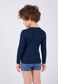 Camicia a maniche lunghe di colore navy realizzata in tessuto morbido, abbinata a pantaloncini blu, che mostra un design semplice e una vestibilità comoda.