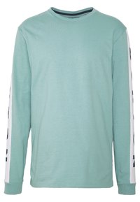 Světle zelená dlouhá košile s dlouhými rukávy vyrobená z měkké látky. Má bílé rukávy s tmavým textem. Kulatý výstřih a žebrované manžety.