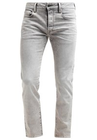 Jeans de mezclilla gris claro con un corte ajustado, que cuentan con cinco bolsillos, cierre de botón y un desvanecimiento sutil en la tela para dar textura.