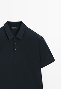 Dunkelblaues kurzärmeliges Polohemd mit klassischem Kragen und drei silbernen Druckknöpfen auf weißem Hintergrund.