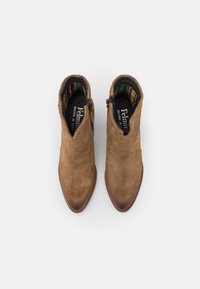 Bottines en daim marron avec un bout pointu et une fermeture éclair sur le côté. Une doublure à motifs colorés est visible à l'ouverture supérieure. Talon lisse.