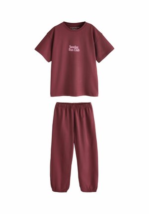Bordová košeľa s krátkym rukávom s textom „Sunday Run Club“ v kombinácii so súpravou nohavíc na jogu s elastickým pásom v rovnakom odtieni na bielom pozadí.