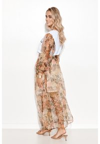 Przezroczysty kwiatowy kimono z długimi rękawami, w odcieniach delikatnego brzoskwiniowego i zielonego, nałożony na białą bluzkę i beżowe sandały.