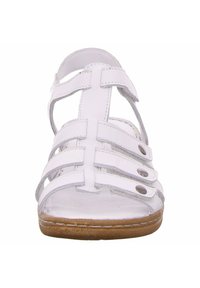 White leather sandal featuring multiple straps, open toe design, and a brown rubber sole. Includes decorative rivets and stitching details.