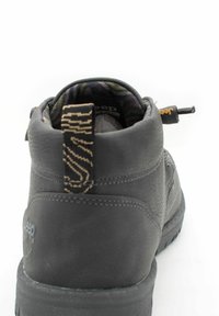 Stivale nero in pelle alla caviglia con superficie texturizzata, fodera decorata e un tassello per il colpo con un design a zigzag sul retro.