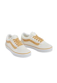 Des baskets en daim blanc avec une bande latérale texturée et des lacets jaunes pailletés, dotées d'une semelle en caoutchouc blanche et de détails jaunes.