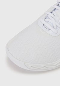 Scarpa da tennis bianca con una parte superiore in tessuto testurizzato caratterizzata da motivi ondulati, lacci bianchi e una suola in gomma liscia. Design minimalista.