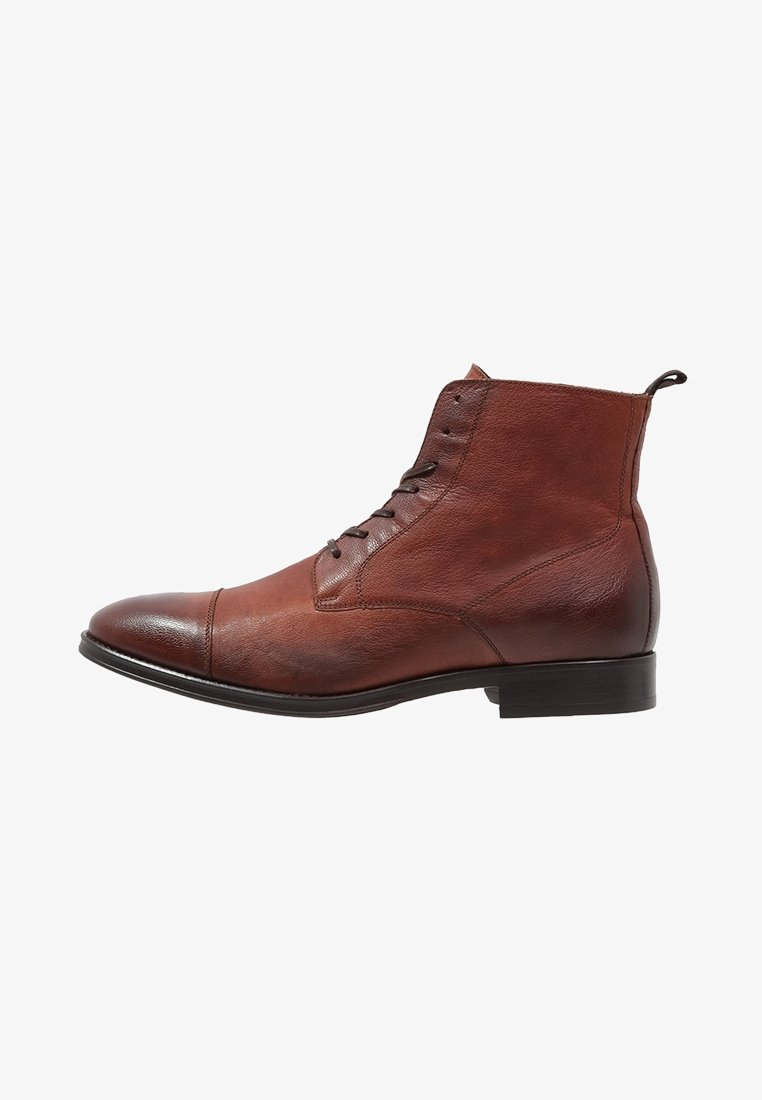 Stivaletto in pelle marrone con punta arrotondata, chiusura con lacci e finitura liscia. Presenta un tacco leggermente rialzato e dettagli di cucitura minimi.