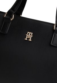 Black leather handbag with textured surface, gold-tone logo hardware. Features dual handles and a structured design.