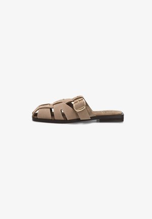 Sandalia plana tipo slide de ante beige con tiras anchas recortadas y una gran hebilla dorada en el lateral, combinada con una suela negra.
